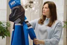 Žena držiaca čerstvo opranú lyžiarsku bundu od Helly Hansen