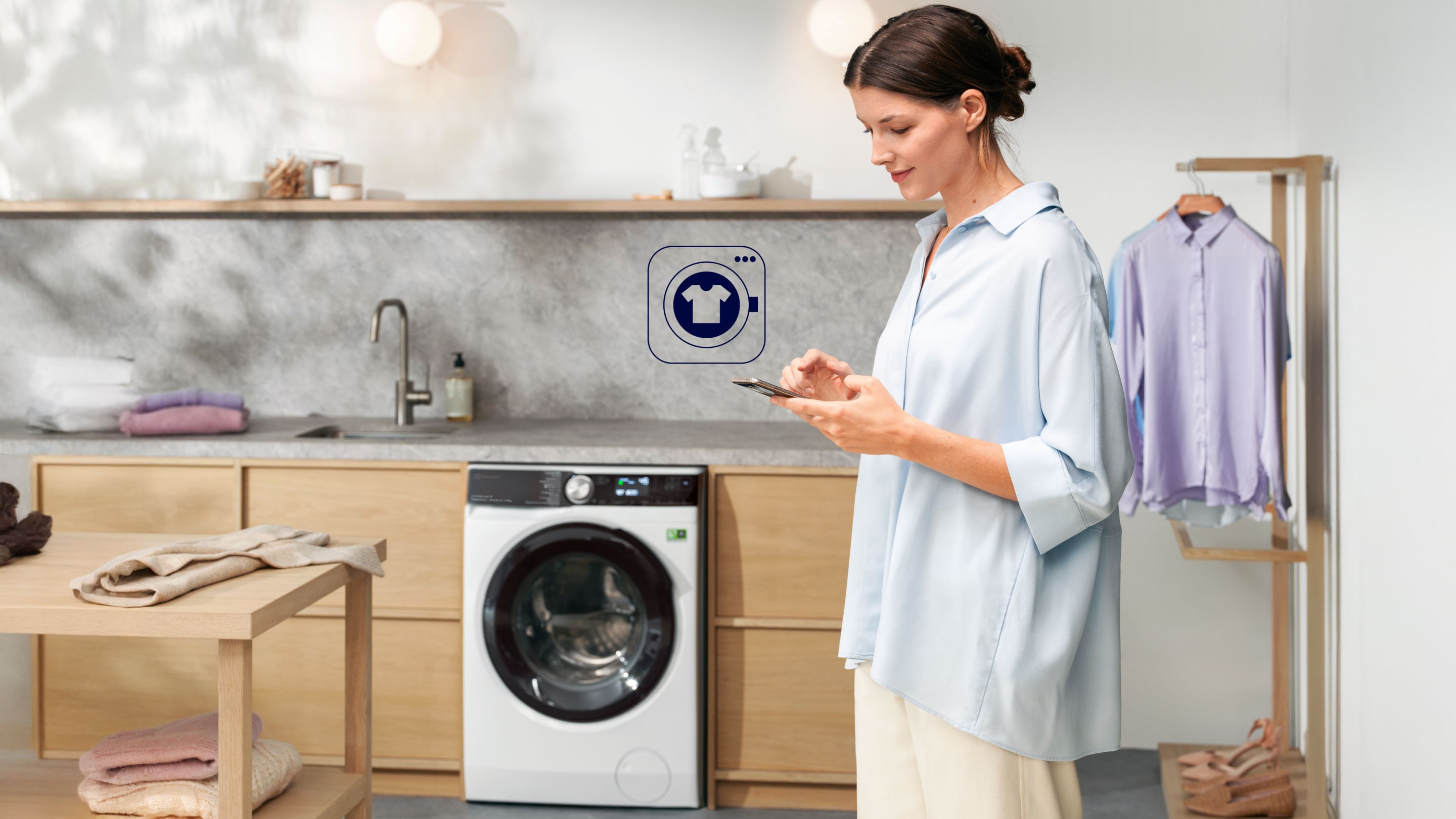 Žena s telefónom stojaca pred práčkou