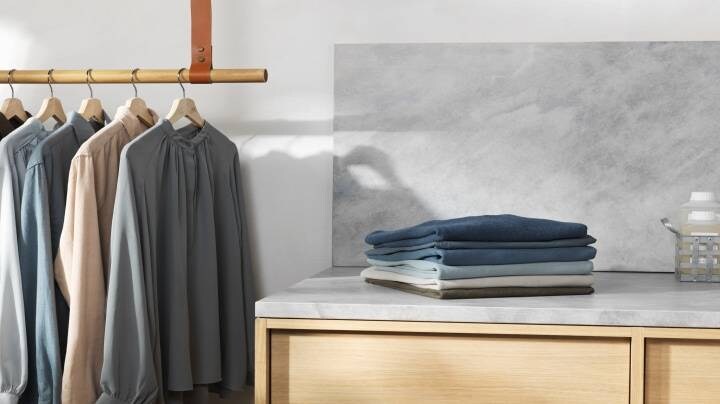 Poskladané oblečenie a oblečenie visiace na ramienku.