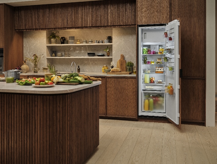 Pohľad do kuchyne s otvorenou chladničkou vzadu.